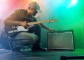 The guitarist tunes the combo amplifier. Stage light. Smoke.
