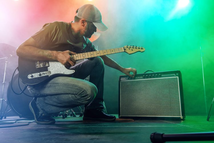 The guitarist tunes the combo amplifier. Stage light. Smoke.