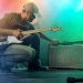The guitarist tunes the combo amplifier. Stage light. Smoke.