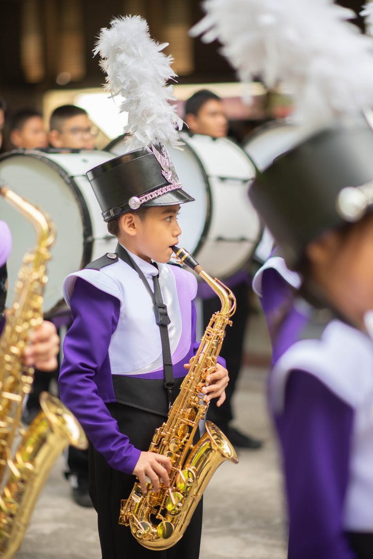 Little boy in purple white uniform play saxophone in  marching band