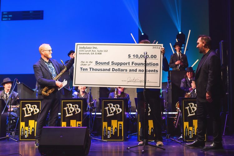 Jody Espina presents a check to Caleb Chapman for JodyJazz’s $10,000 donation to the Sound Support Foundation at their recent Scholarship concert in Salt Lake City